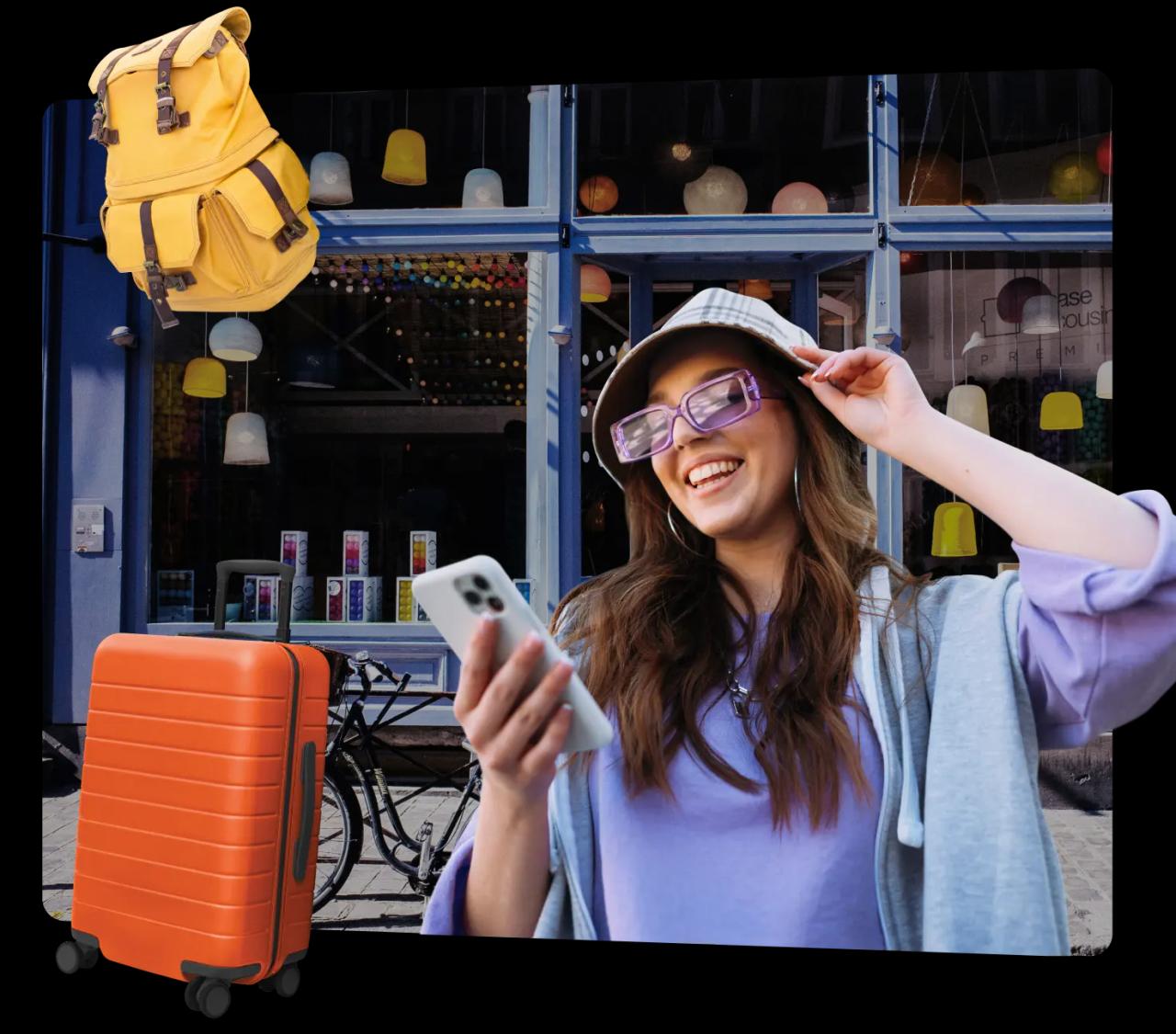 A smiling young woman looks down at her phone in front of a Bounce location. A yellow backpack and orange suitcase are next to her, which will be kept safe while she explores.